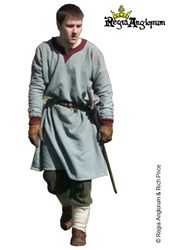 Norman Miles AD1042‑1179 He wears a woad dyed tunic with a round keyhole neck and long rucked sleeves. At his waist he carries a sword.