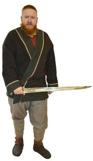 Wearing a military lined and decorated wrap-around jacket, pinned at the hip by a ringed pin. These 'warrior jackets' are adopted from the mounted warriors from Eastern Europe. He carries a single-edged sword, typical of Norwegian Vikings